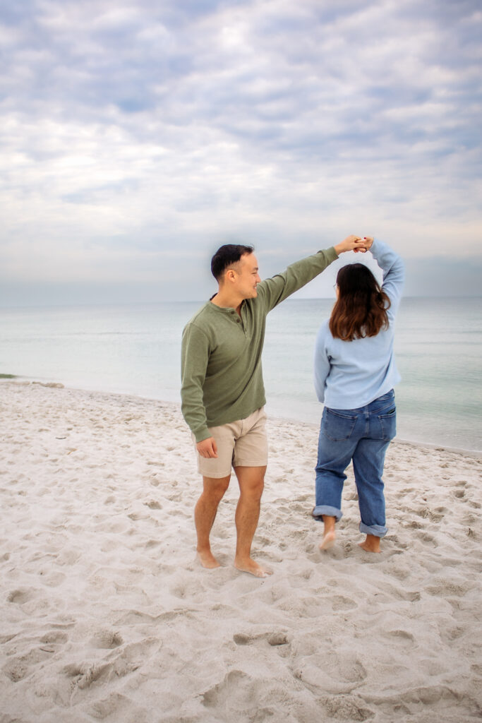 Couple engagement photos on a beach of  man spinning a woman