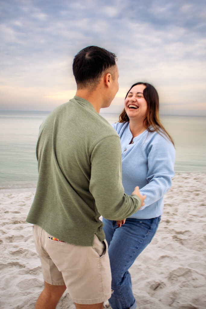 Couple engagement photos on a beach of couple laughing together