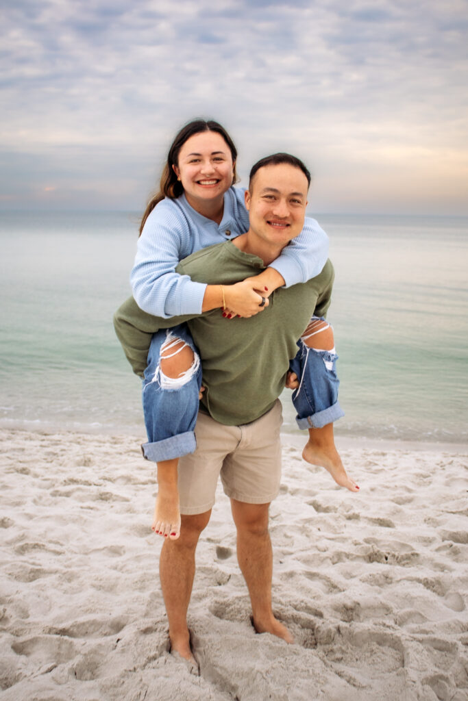 Couple engagement photos on a beach of couple doing a piggyback