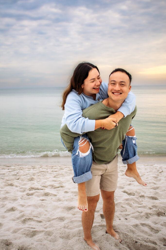 Couple engagement photos on a beach with a piggy back