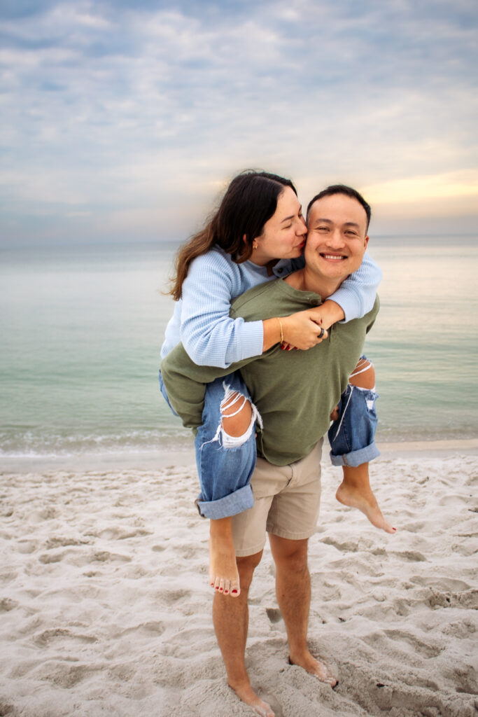 Couple engagement photos on a beach of couple doing a piggyback