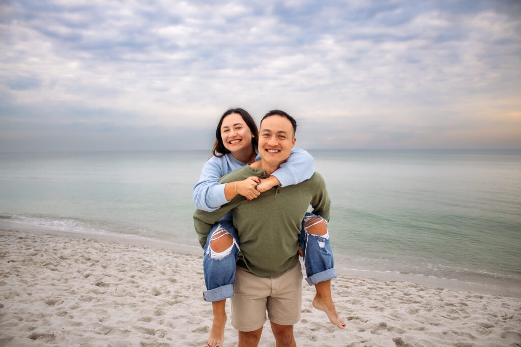 Couple engagement photos on a beach of couple doing a piggyback